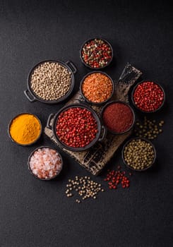 Variations of spices, allspice, turmeric, paprika, salt in ceramic bowls on a dark concrete background
