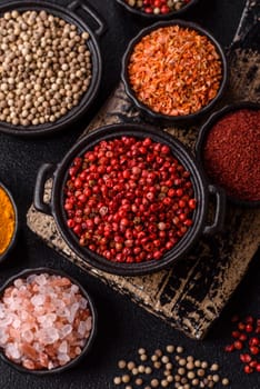 Variations of spices, allspice, turmeric, paprika, salt in ceramic bowls on a dark concrete background