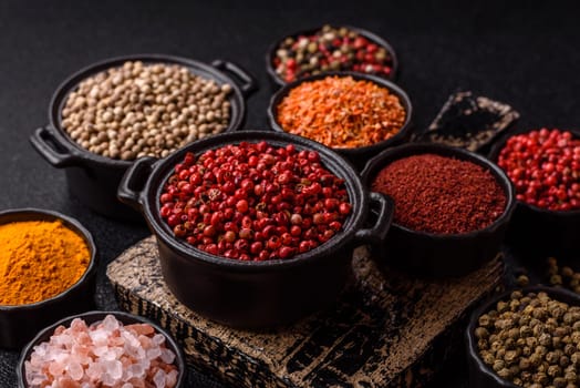 Variations of spices, allspice, turmeric, paprika, salt in ceramic bowls on a dark concrete background