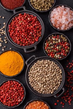 Variations of spices, allspice, turmeric, paprika, salt in ceramic bowls on a dark concrete background