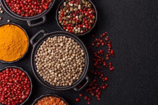 Variations of spices, allspice, turmeric, paprika, salt in ceramic bowls on a dark concrete background