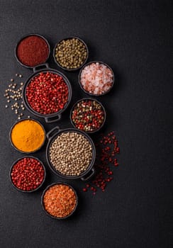 Variations of spices, allspice, turmeric, paprika, salt in ceramic bowls on a dark concrete background