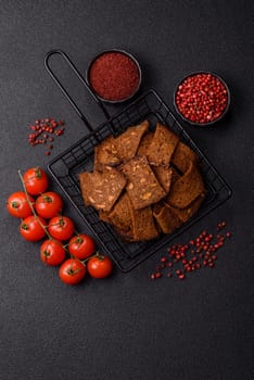 Crispy homemade brown bread chips with seeds and grains, salt, spices and herbs on a dark concrete background