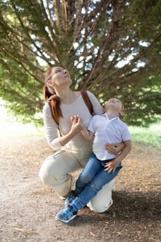 A woman and a child are sitting in a park. The woman is holding the child's hand