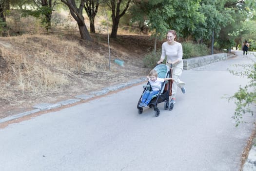 A woman pushing a stroller with a child in it. The child is smiling and the woman is smiling as well. The scene is peaceful and happy