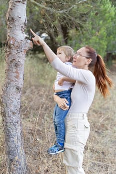 A woman and a child are looking at a tree, day