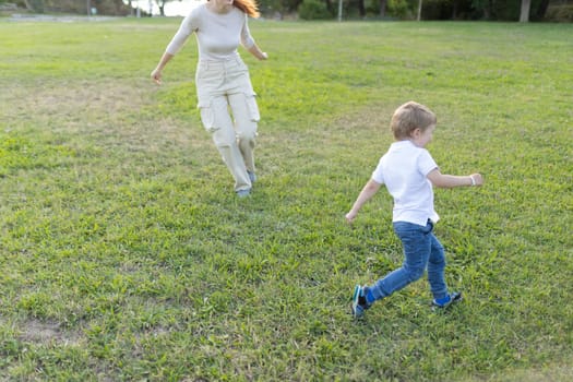 Mother and her son are running through a park together on a sunny day
