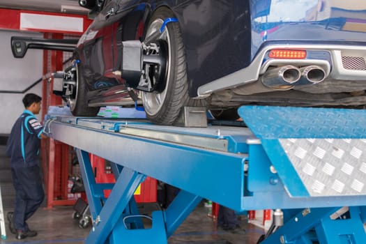 Serviceman checking suspension in a car at garage