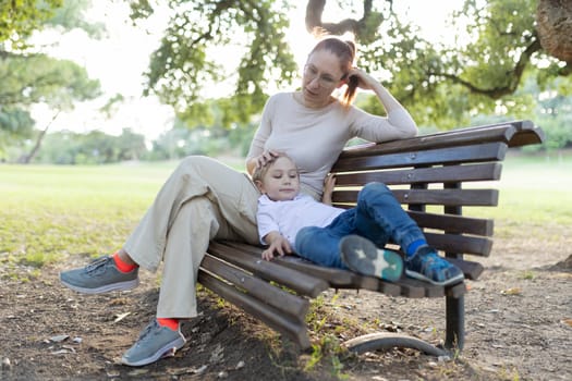 Mother and son are sitting on a park bench, enjoying a quiet moment together