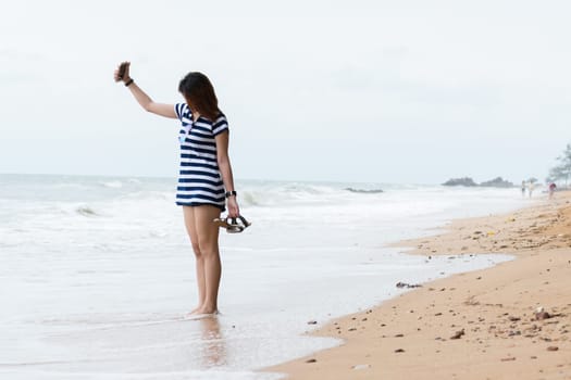 Asia woman walking at beach with blue sea and sky when travel