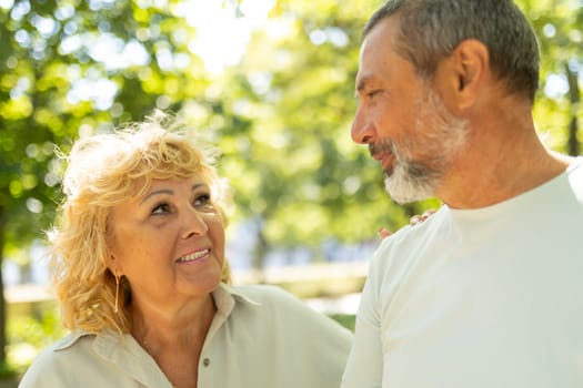 Affectionate senior couple is sharing a tender moment while taking a leisurely stroll in a lush green park