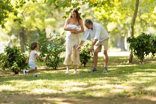 Young family is enjoying a walk together in the park on a sunny summer day