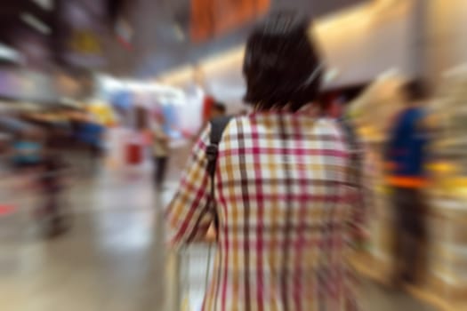Blurred zoom of Thai woman shopping by shopping cart in Department store or shopping mall is a popular destination for walks and relaxing family in holiday.