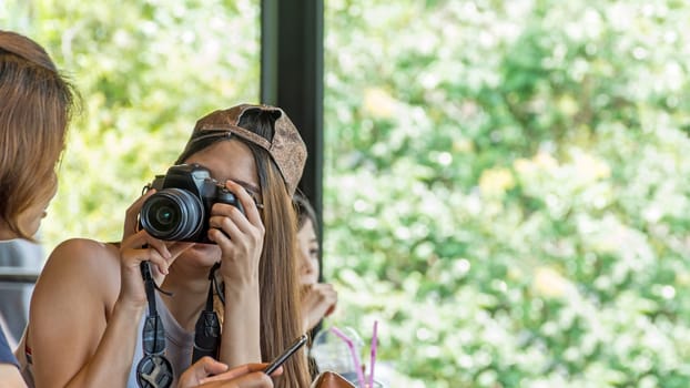 Asia woman take a photo by her camera at restaurant or cafe when travel with her best friends