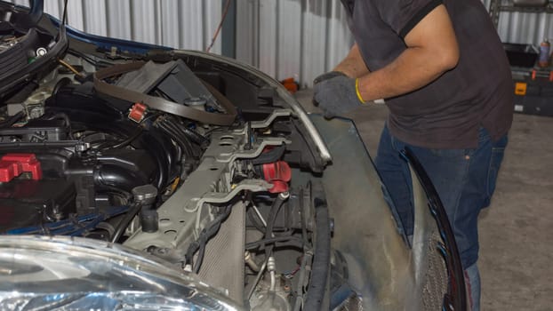 Serviceman checking a car for fix and repair at garage