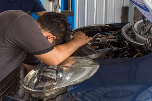 Serviceman checking a car for fix and repair at garage