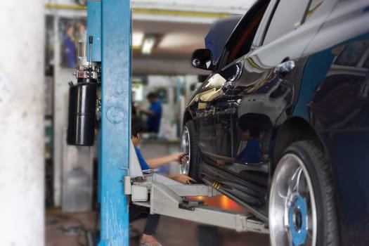 Serviceman checking suspension in a car at garage