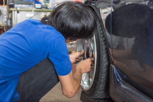 Serviceman checking suspension in a car at garage