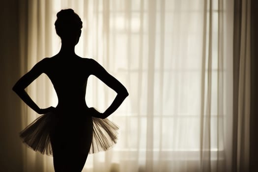 Silhouette of beautiful classical young ballerina standing by the window in light and shadow in ballet studio