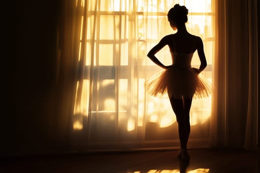 Silhouette of beautiful classical young ballerina standing by the window in light and shadow in ballet studio