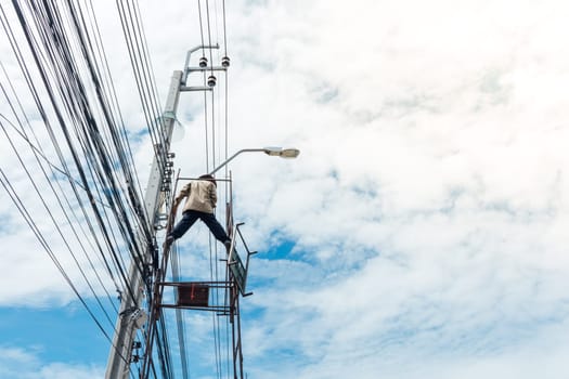 Worker working to install electric line by scaffolding on pickup truck at Bangkok Thailand.