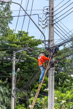 Worker working to install electric line by scaffolding on pickup truck at Bangkok Thailand.