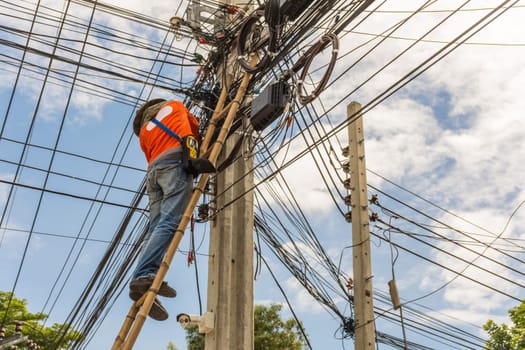Worker working to install electric line by scaffolding on pickup truck at Bangkok Thailand.