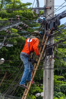 Worker working to install electric line by scaffolding on pickup truck at Bangkok Thailand.