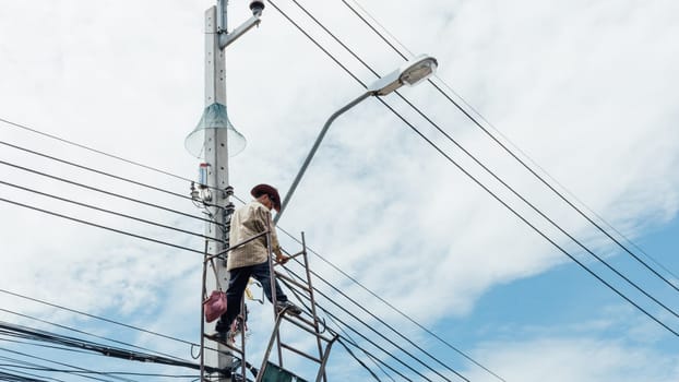 Worker working to install electric line by scaffolding on pickup truck at Bangkok Thailand.