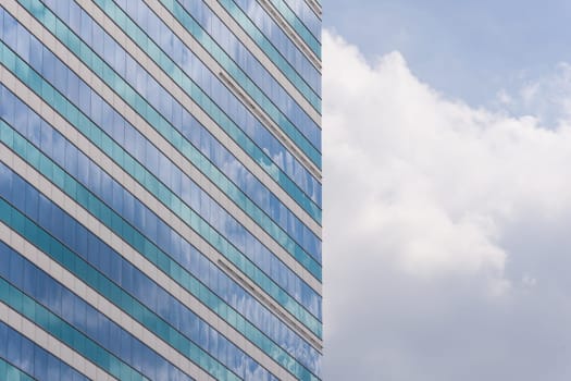 Big glass office building with blue sky and white cloud