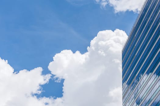 Exterior of glass office building reflection with blue sky and white cloud in a city with business, finance, construction and global warming concept