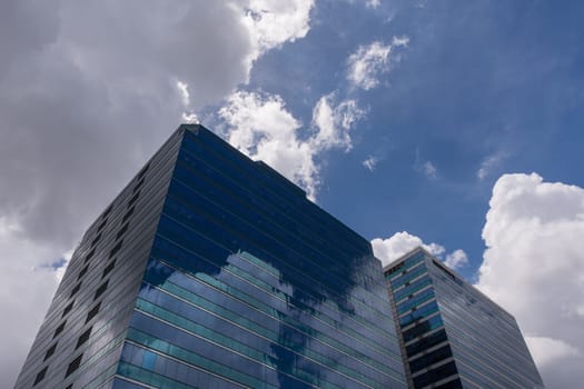 Big glass office building with blue sky and white cloud