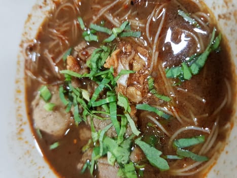 Braised beef clear noodle with meat balls soup stew (Ekaehla meat) with vegetable in bowl for sale at Thai street food market or restaurant in Thailand