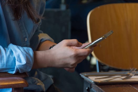 Mobile phone and women on wood table in coffee shop or restaurant
