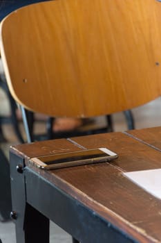Mobile phone on wood table in coffee shop or restaurant