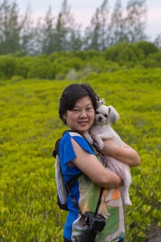 Asia woman plump body in colorful dress and her dog posing at Mangrove forrest or Golden Meadow (Thung Prong Thong in Thai language) is a nalure travel point at Rayong, Thailand
