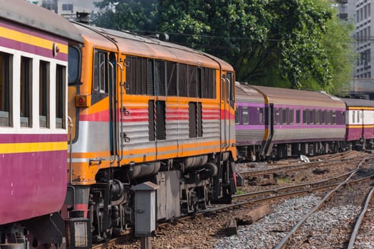 Railway train on the railroad tracks in Bangkok station. Many people in Thailand popular travel by train because it is cheaper.