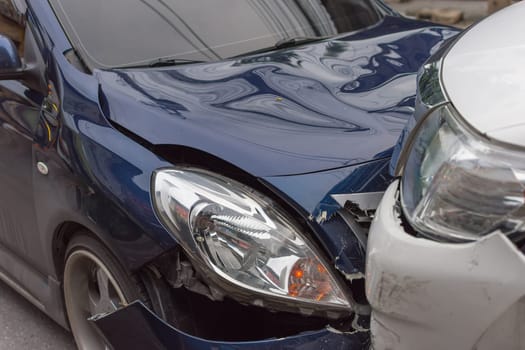 Car crash from car accident on the road in a city between saloon versus pickup wait insurance.