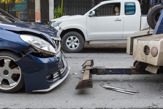 Car crash from car accident on the road in a city between saloon versus pickup wait insurance.