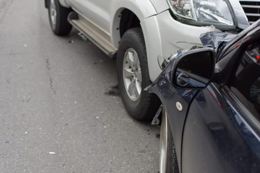 Car crash from car accident on the road in a city between saloon versus pickup wait insurance.