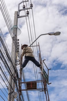 Worker working to install electric line by scaffolding on pickup truck at Bangkok Thailand.