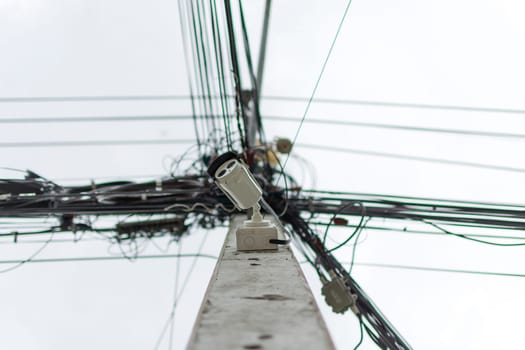 Security camera (CCTV) for safety on pole of electric line and communication with messy line background