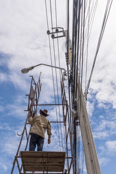 Worker working to install electric line by scaffolding on pickup truck at Bangkok Thailand.