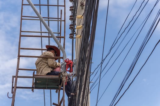 Worker working to install electric line by scaffolding on pickup truck