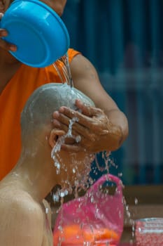 Thai monk clean a head of man by water after hair shave for ordination ceremony in buddhist in Thailand