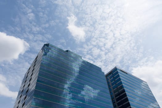Big glass office building with blue sky and white cloud