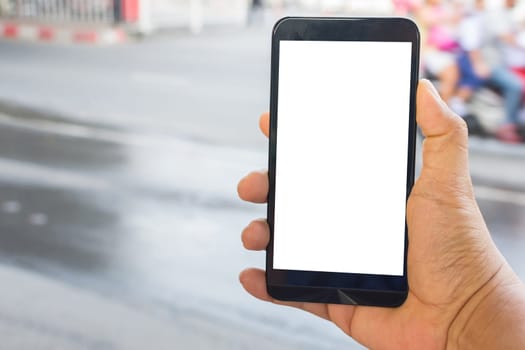 Person hand holding smartphone or mobile phone with white screen using on road