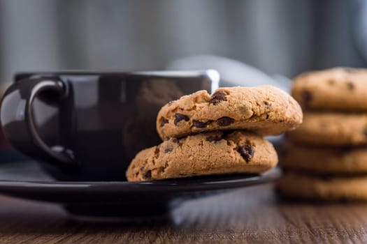 Chocolate chip cookies and coffee cup on a wooden table.