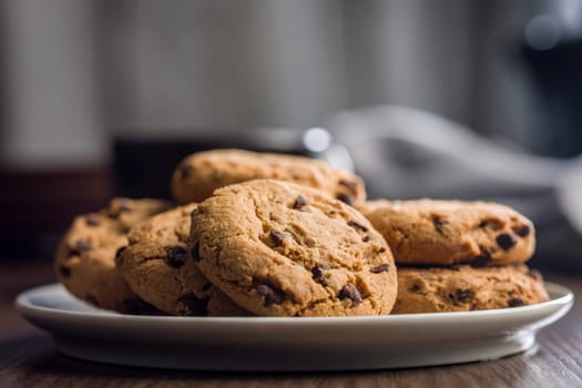 Chocolate chip cookies on plate on a wooden table.