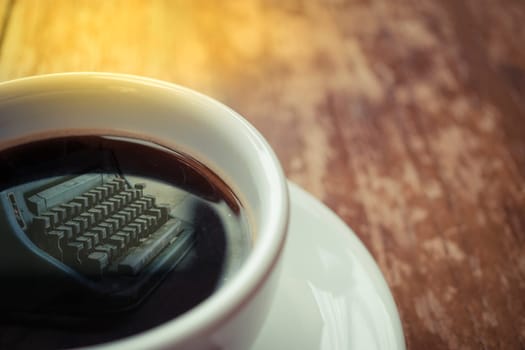 Typewriter reflection on Coffee in white cup on wood table , process in soft orange sun light style